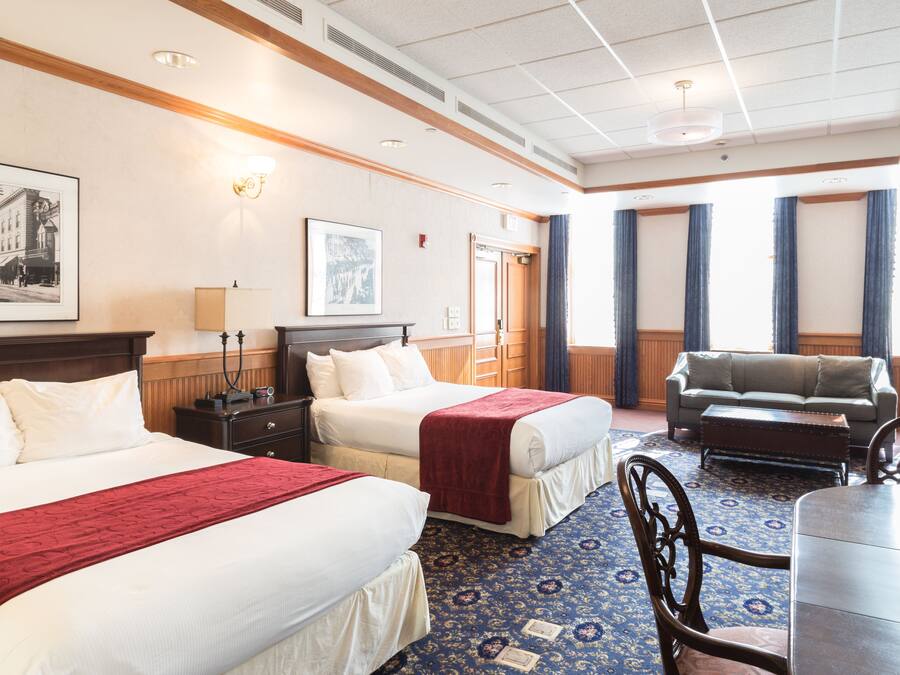 Een hotelkamer met twee bedden, een bank, een eettafel en een kroonluchter.