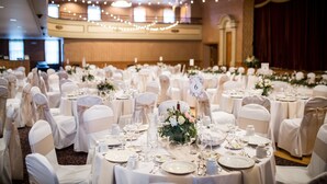 A banquet hall with round tables set for a formal event, each with a number sign. - Hotel Winneshiek (Decorah)
