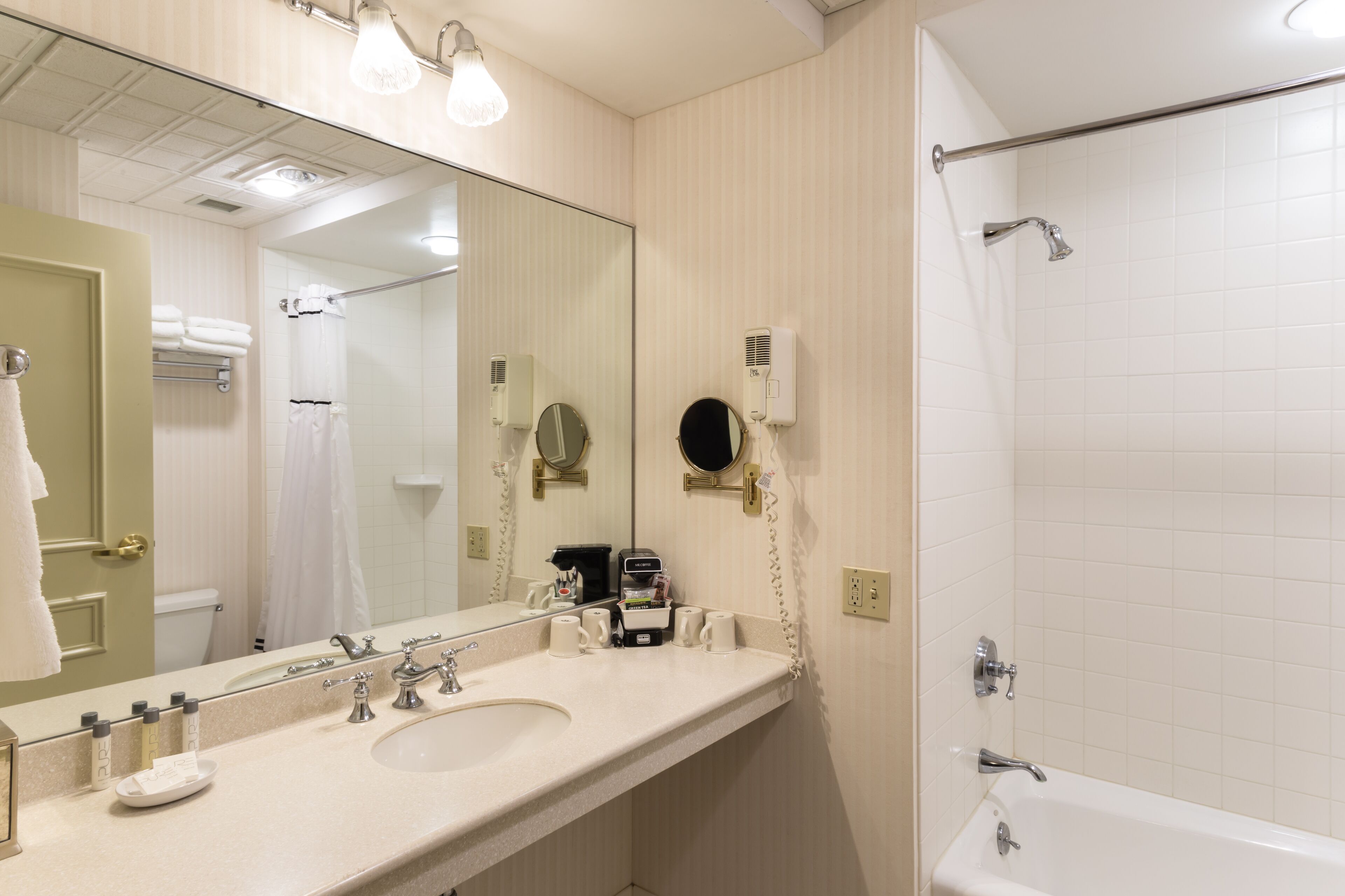 Une salle de bain d’hôtel avec un lavabo, un miroir et une douche.