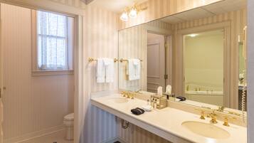 A bathroom with two sinks, a large mirror, and a window.