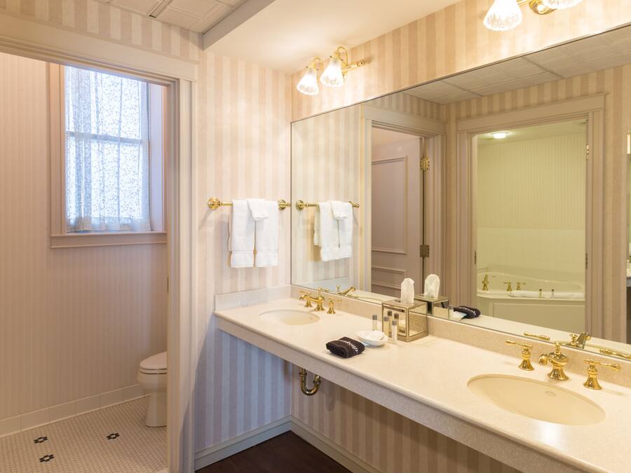 A bathroom with two sinks, a large mirror, and a window.