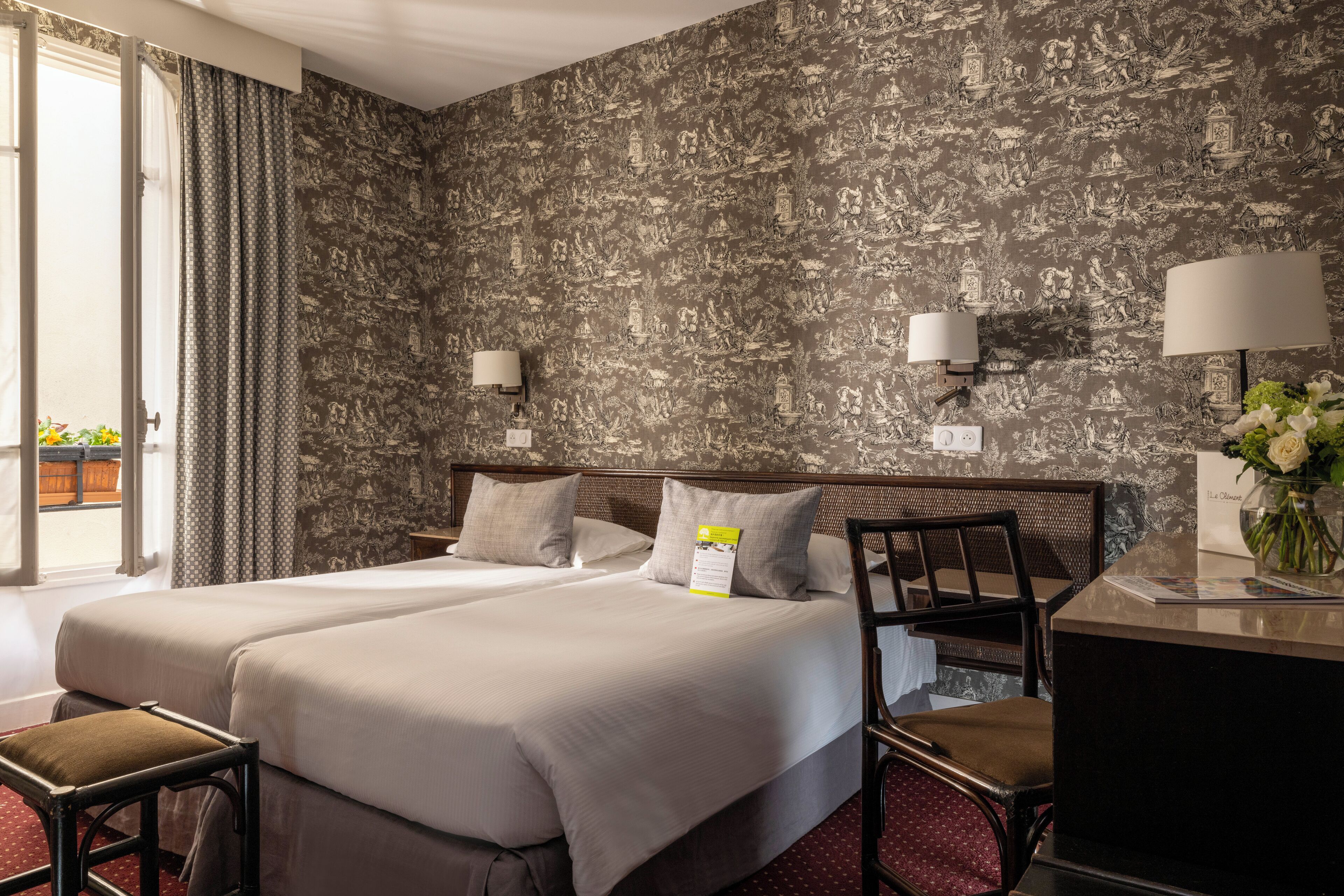 A hotel room with two beds, a desk, and a chair.