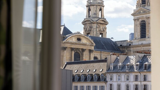 A historic building with a prominent tower and a dome, viewed through a window. - Hôtel Clément (Paris)