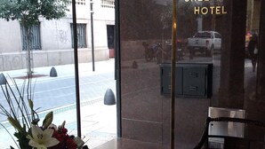 A reception area with a glass wall, a vase of flowers, a magazine on a table, and a red chair. - Hotel Sheltown (Buenos Aires)