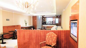 A hotel lobby with a reception desk, seating area, and a television screen. - Hotel Sheltown (Buenos Aires)