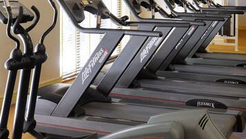 File di tapis roulant in una palestra, con un televisore montato a parete.