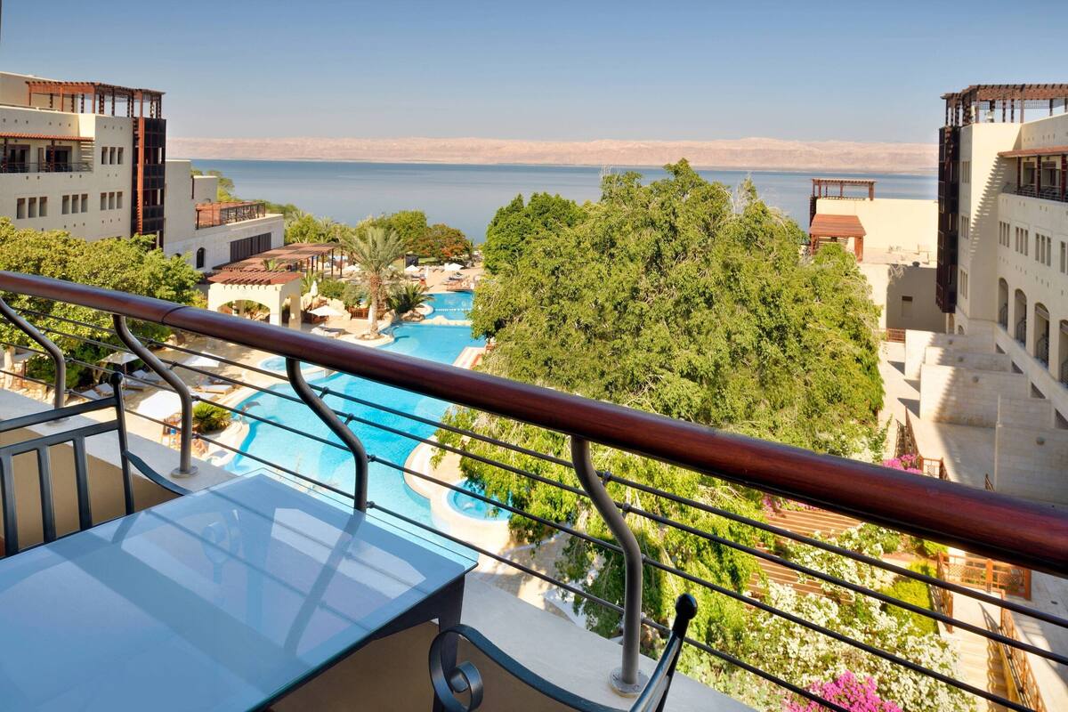 A balcony with a view of a swimming pool and a beach.