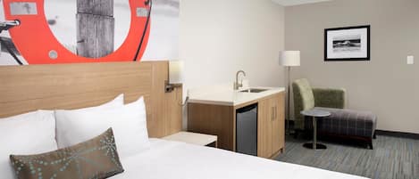 A hotel room with a bed, a desk with a sink, a chair, and a small table.
