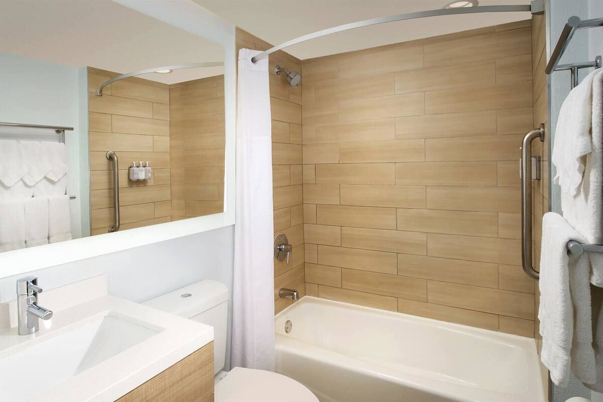 A modern bathroom with a shower, toilet, sink, and a mirror.