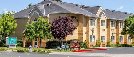 A hotel with a sign reading "Quality Inn & Suites" and a parking lot in front.