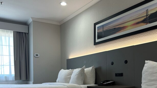 A hotel room with two beds, a headboard with a mounted phone, and a painting above the headboard. - Econo Lodge Inn & Suites Santa Rosa South (Santa Rosa)