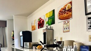 A kitchen area with a coffee machine, a refrigerator, and a microwave. There are posters on the wall and a counter with a bowl of fruit. - Econo Lodge Inn & Suites Santa Rosa South (Santa Rosa)