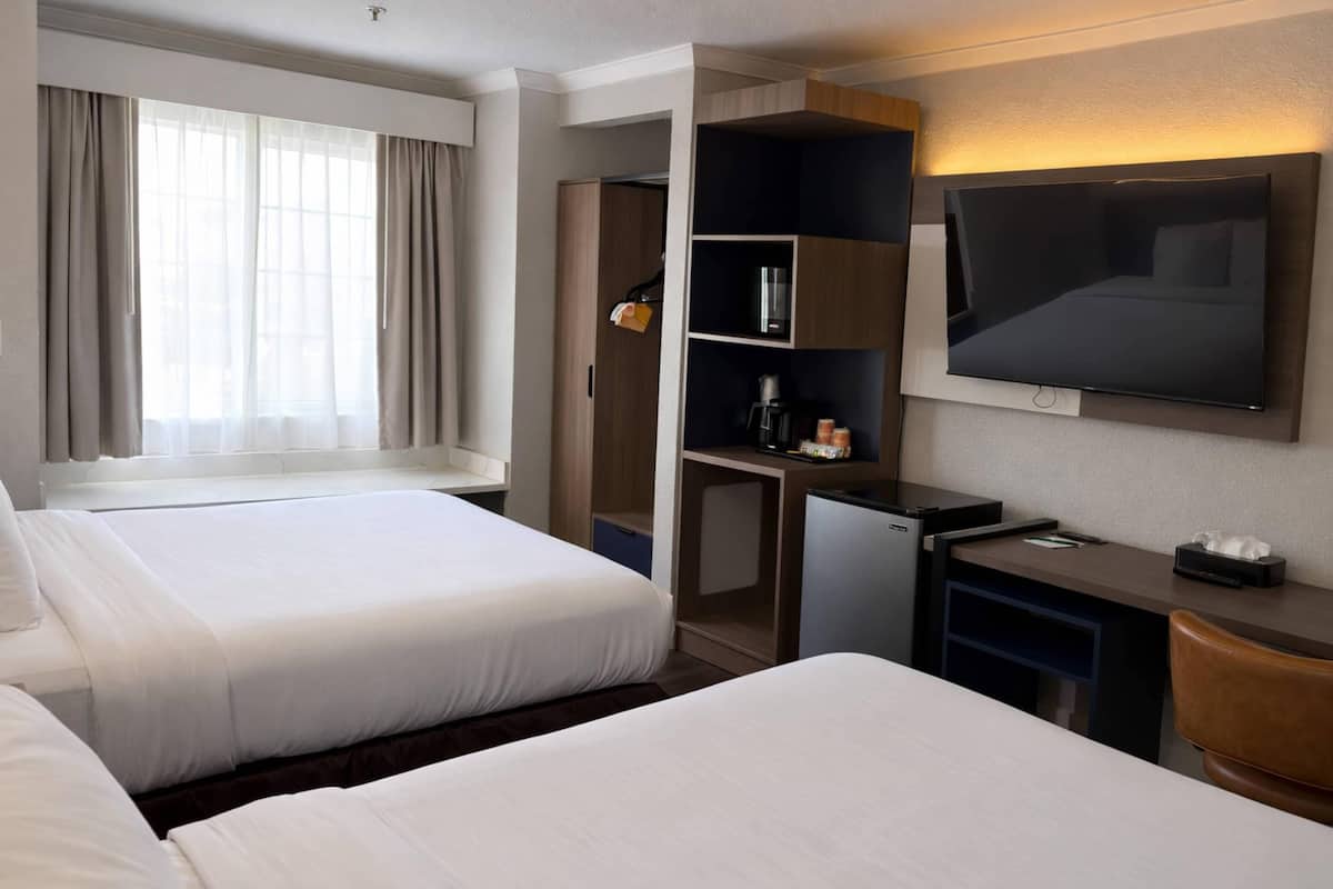 A hotel room with two beds, a desk, a television, and a wardrobe.