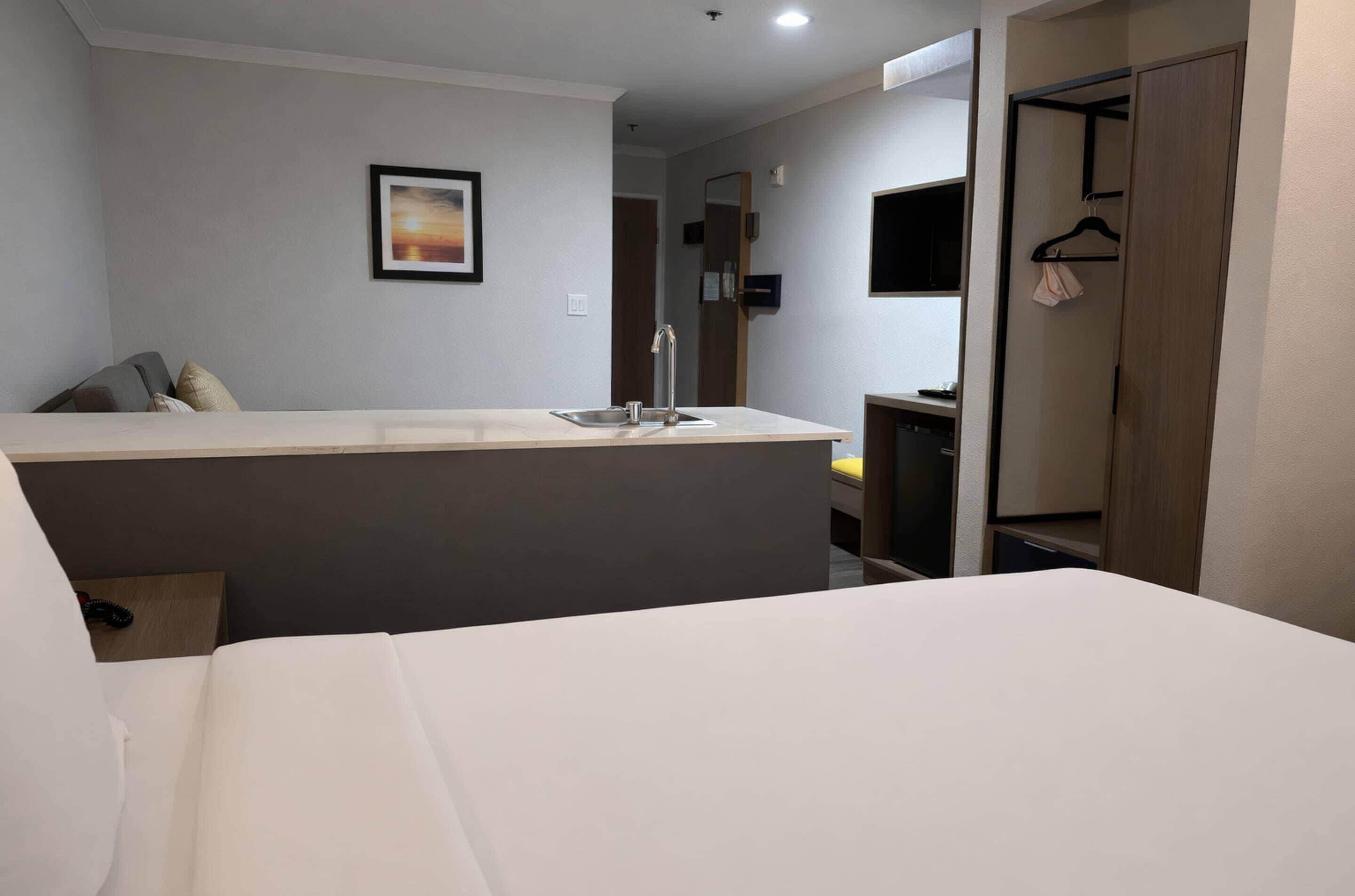 Une chambre d’hôtel avec un lit, un petit bureau doté d’un lavabo, une armoire et un tableau encadré au mur.