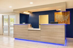 A reception desk with a blue-lit base, a wooden wall with a map of the USA, and a door to the left. - Microtel Inn & Suites by Wyndham New Ulm (New Ulm)