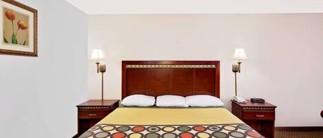 Habitación de hotel con una cama grande, dos mesitas de noche, un cabecero de madera y una lámpara de pared.