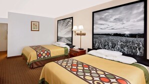 Ein Hotelzimmer mit zwei Betten, einem Nachttisch, einer Lampe und großen gerahmten Bildern an der Wand.