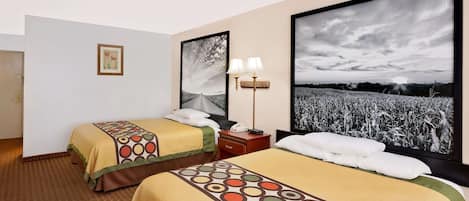 Une chambre d’hôtel avec deux lits, une table de chevet, une lampe et de grandes images encadrées accrochées au mur.
