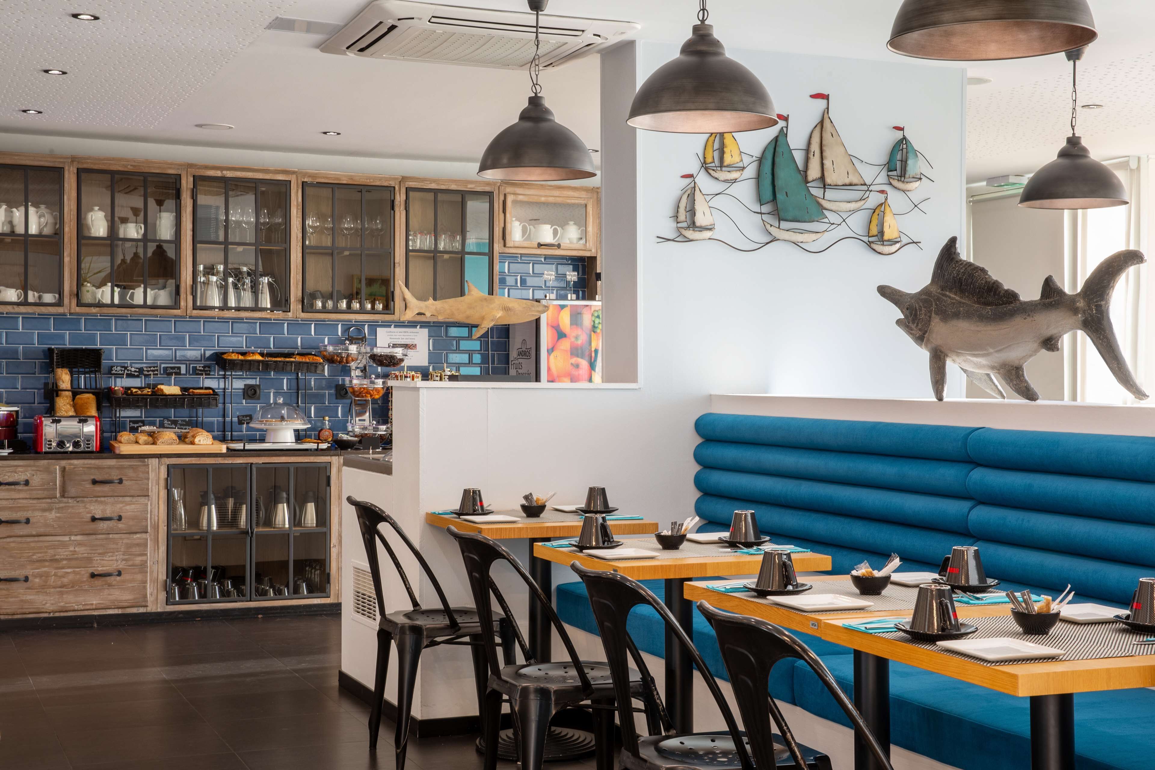 A restaurant with wooden cabinets, blue tiled backsplash, and a blue booth seating area.