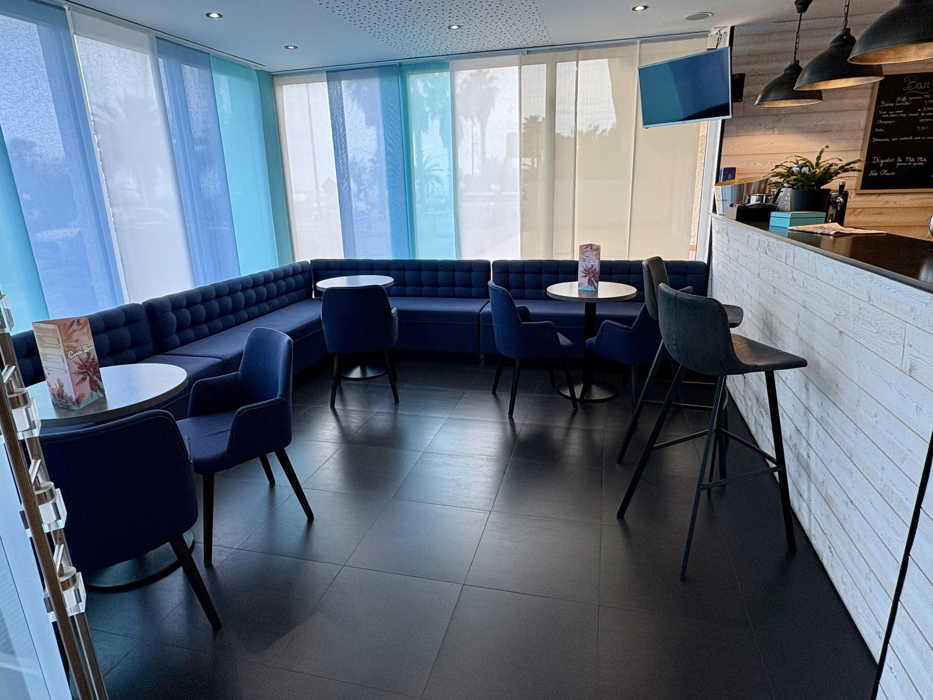 A modern restaurant with a blue seating area, including a sofa and round tables.