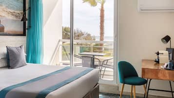 Een hotelkamer met een bed, een bureau, een stoel en uitzicht op de oceaan.