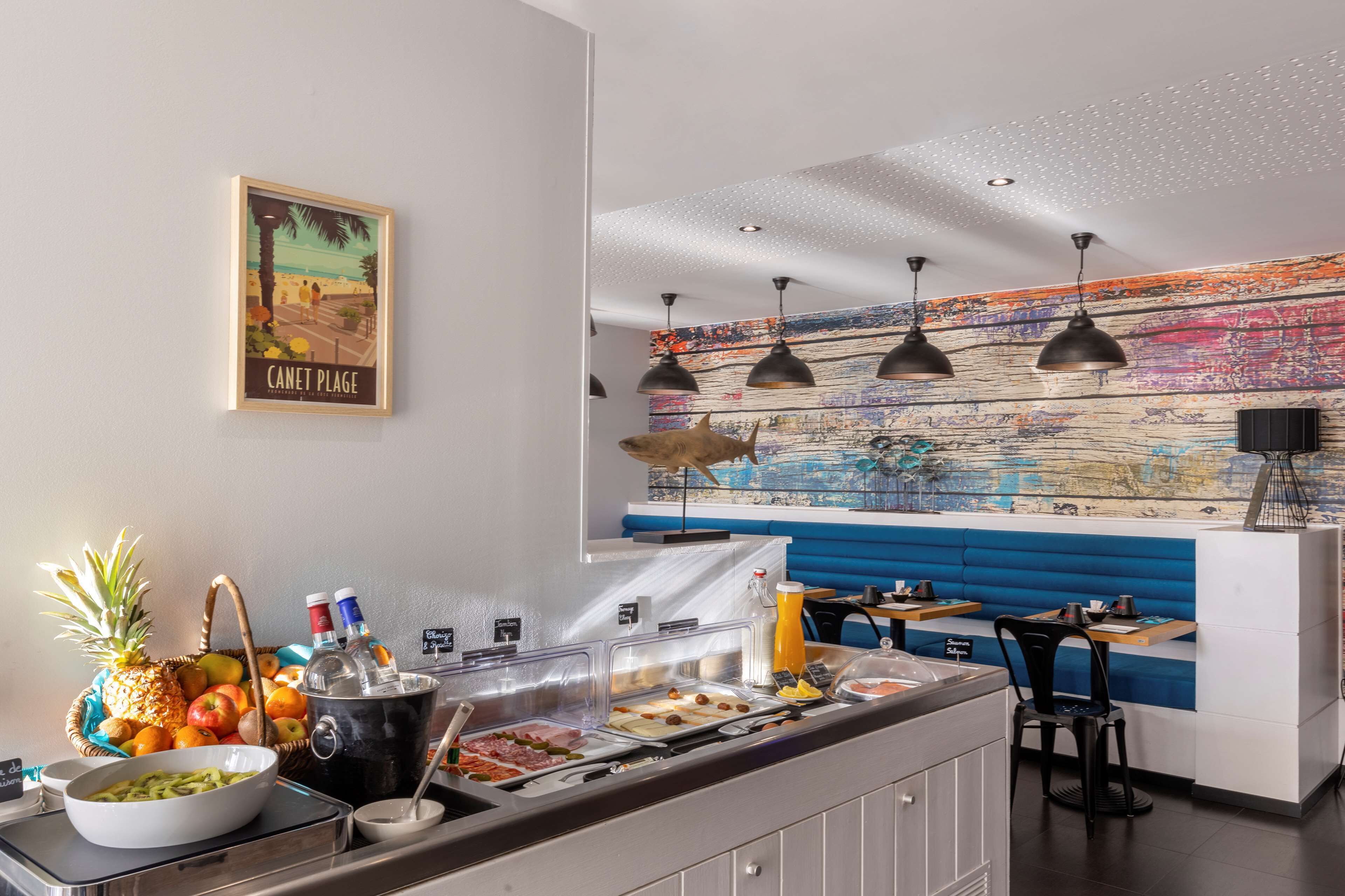 A breakfast buffet with a variety of food options, a fruit basket, and a mural on the wall.