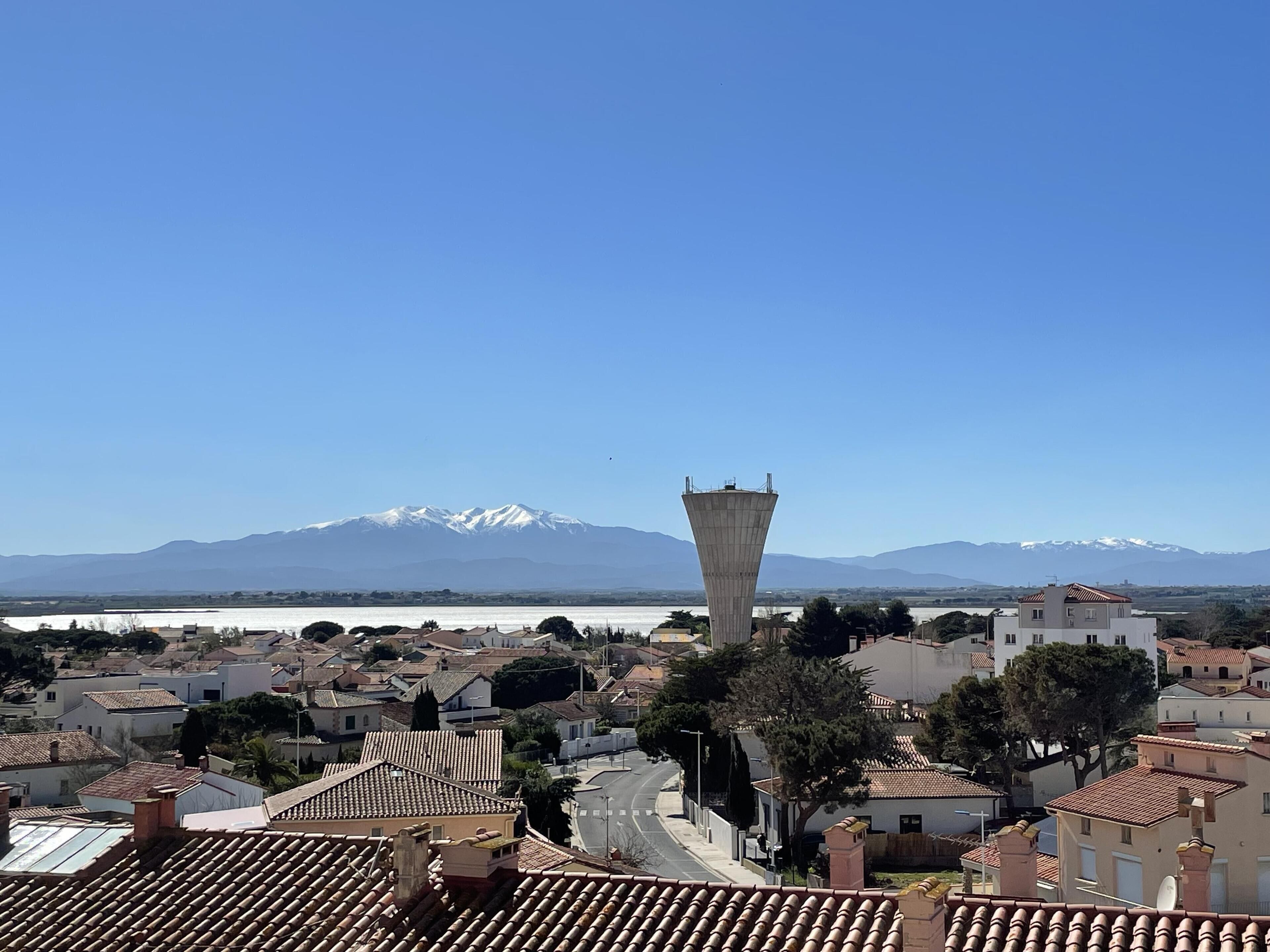 Un quartier résidentiel avec une tour imposante et une chaîne de montagnes en arrière-plan.