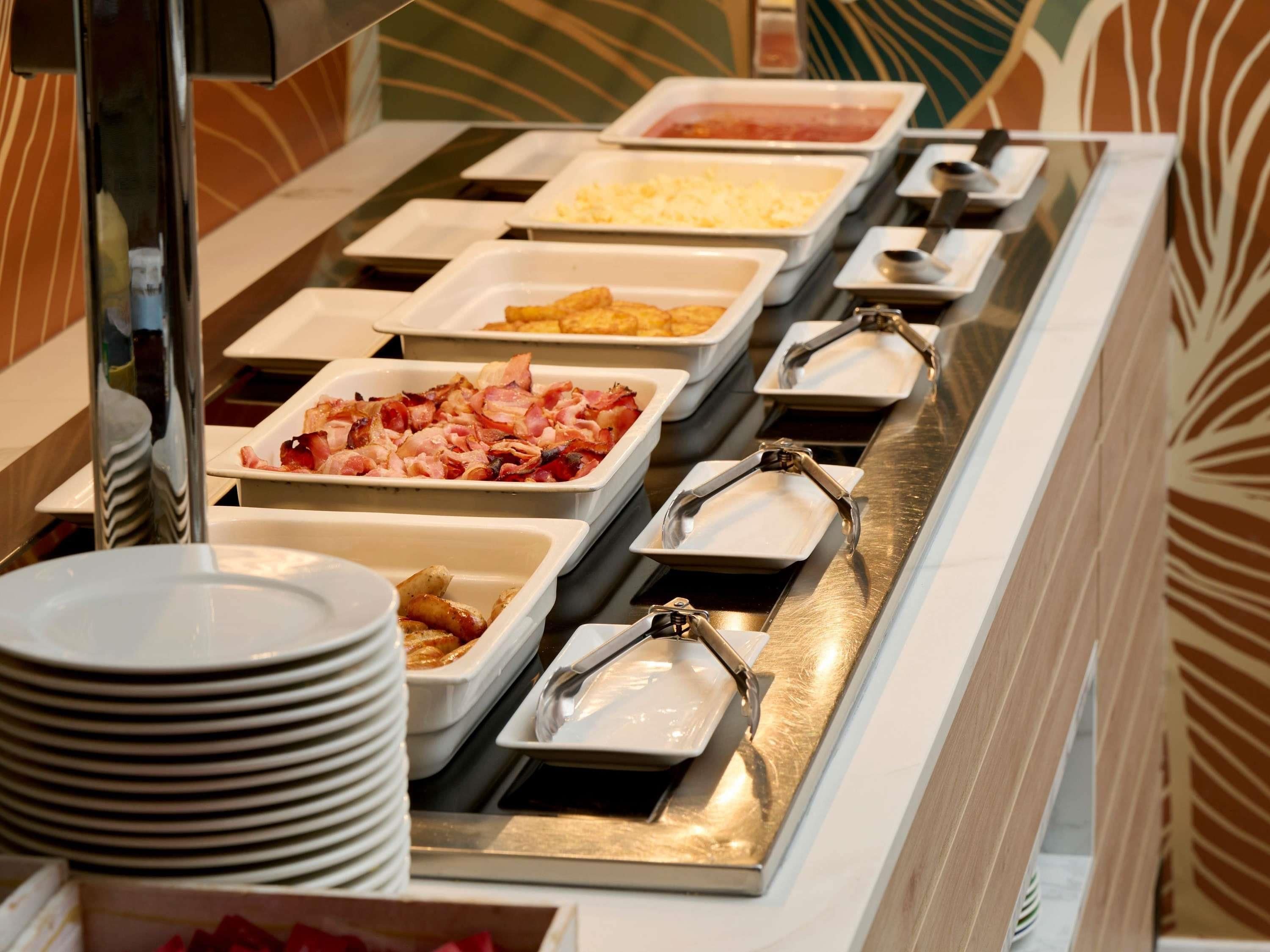 Un buffet con diverse opzioni gastronomiche, tra cui bacon, formaggio e altri piatti.