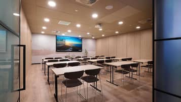 Une salle de conférence équipée d’un grand écran, de plusieurs tables et de chaises.