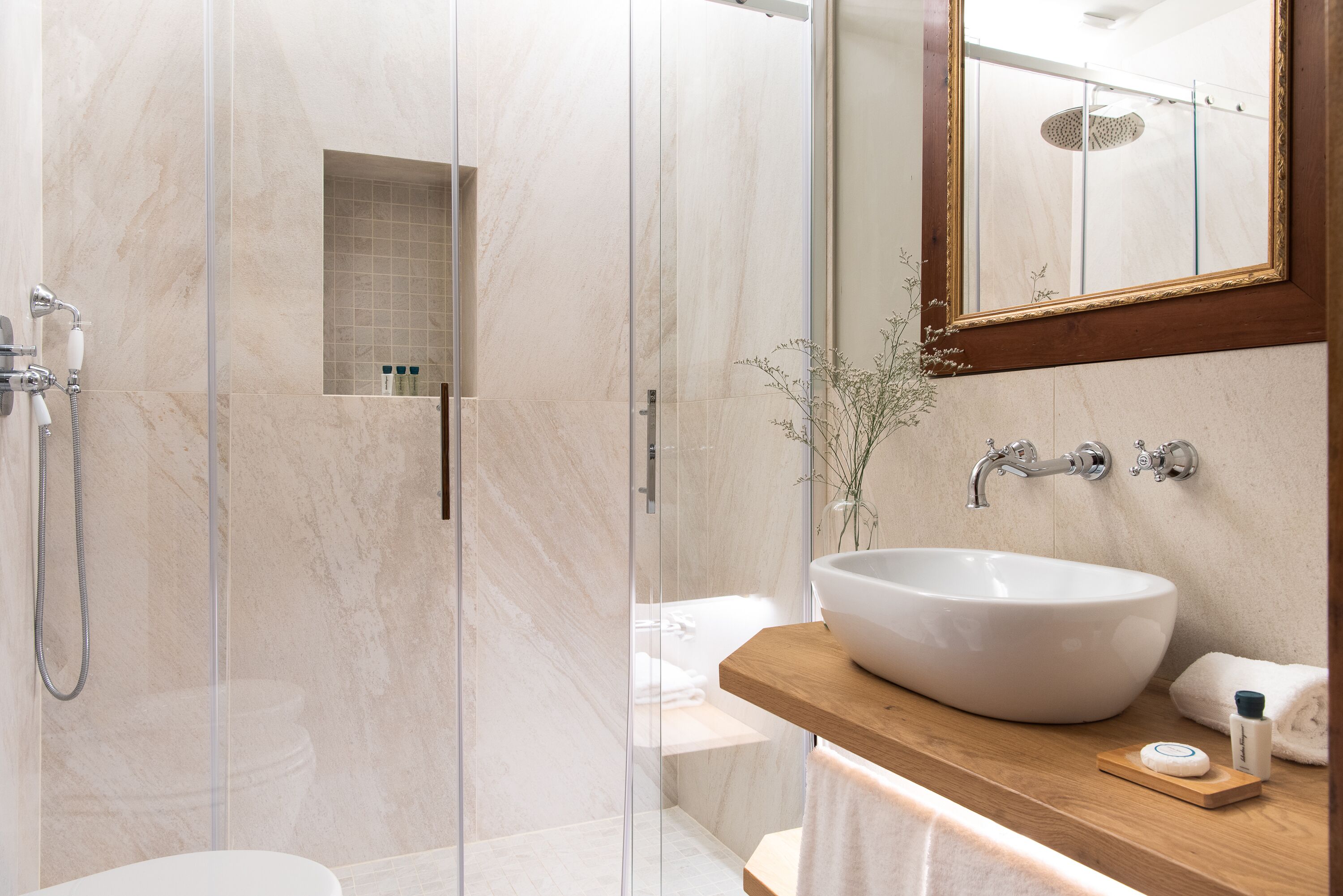 A modern bathroom with a glass-enclosed shower, a large white sink, and a wooden vanity.