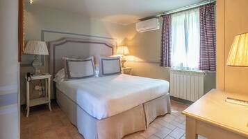 A hotel room with a bed, bedside lamps, a table, and a window with curtains.