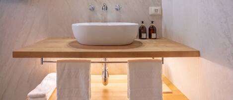 A bathroom with a large vessel sink, wooden countertop, two towel racks, and a mirror above the sink.