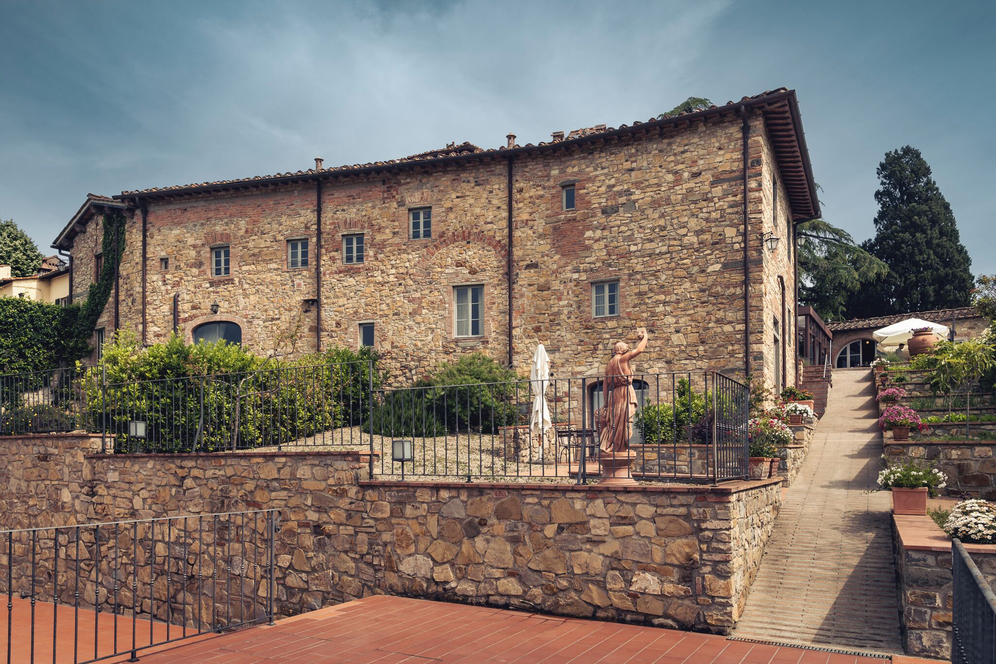 A stone building with a balcony, a statue, and a staircase leading to an entrance.