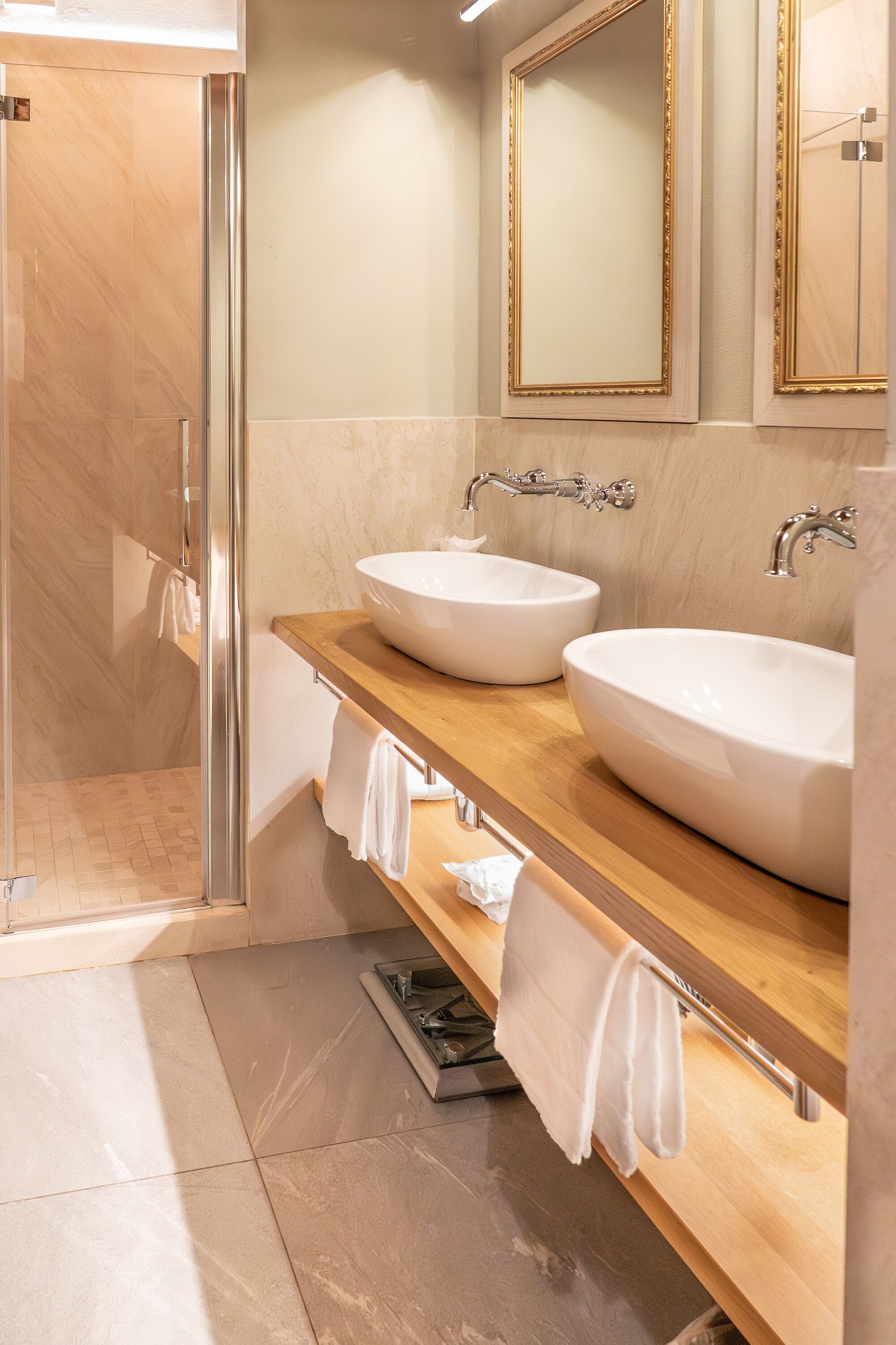 A bathroom with two sinks, a mirror, and a shower.