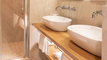 A bathroom with two sinks, a mirror, and a shower.