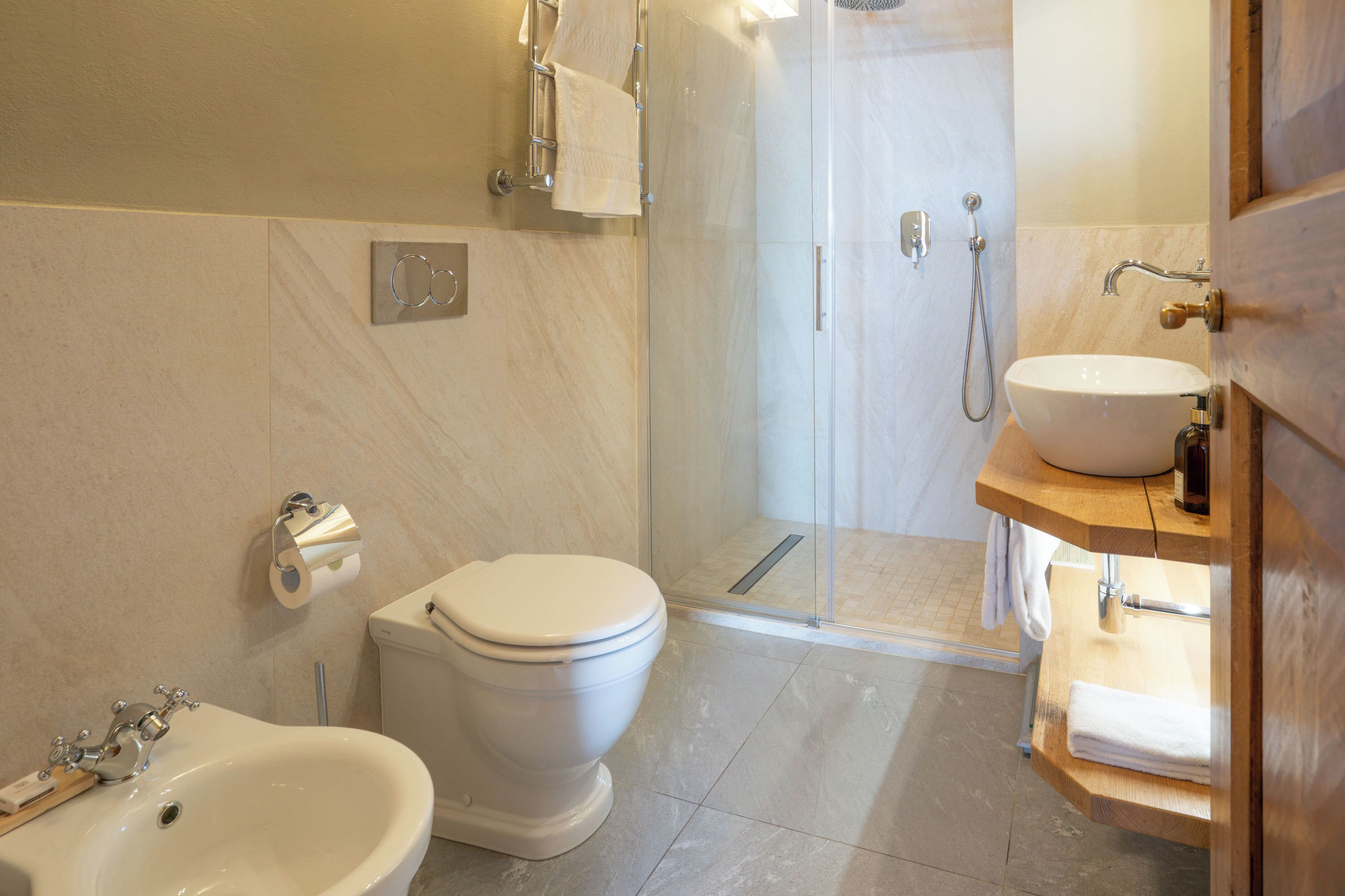 Een moderne badkamer met toilet, hygiëneschuimer, wastafel en douche.