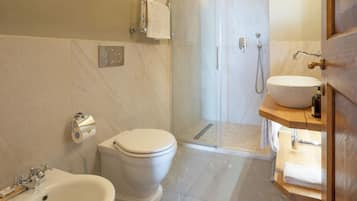 Een moderne badkamer met toilet, hygiëneschuimer, wastafel en douche.