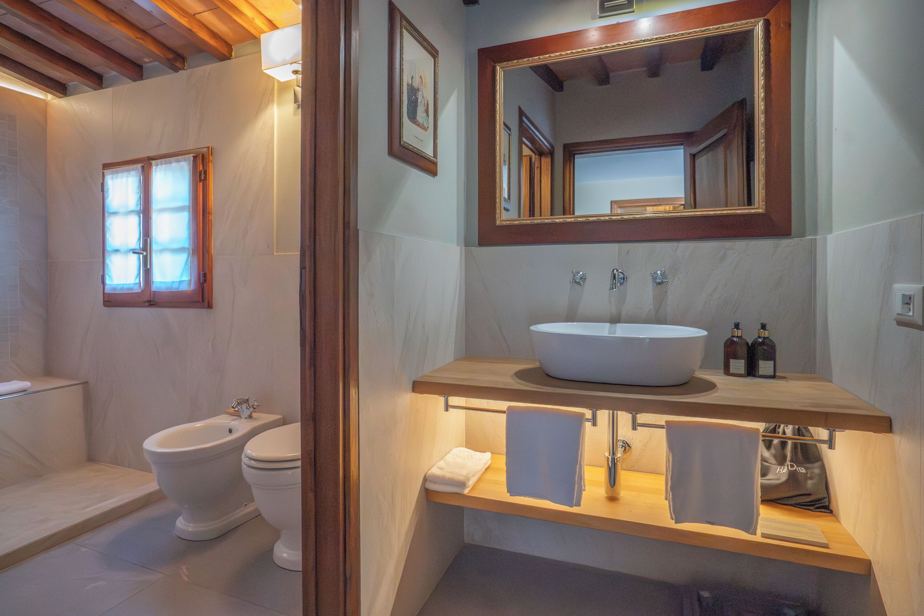 A bathroom with a bidet, toilet, sink, and mirror.