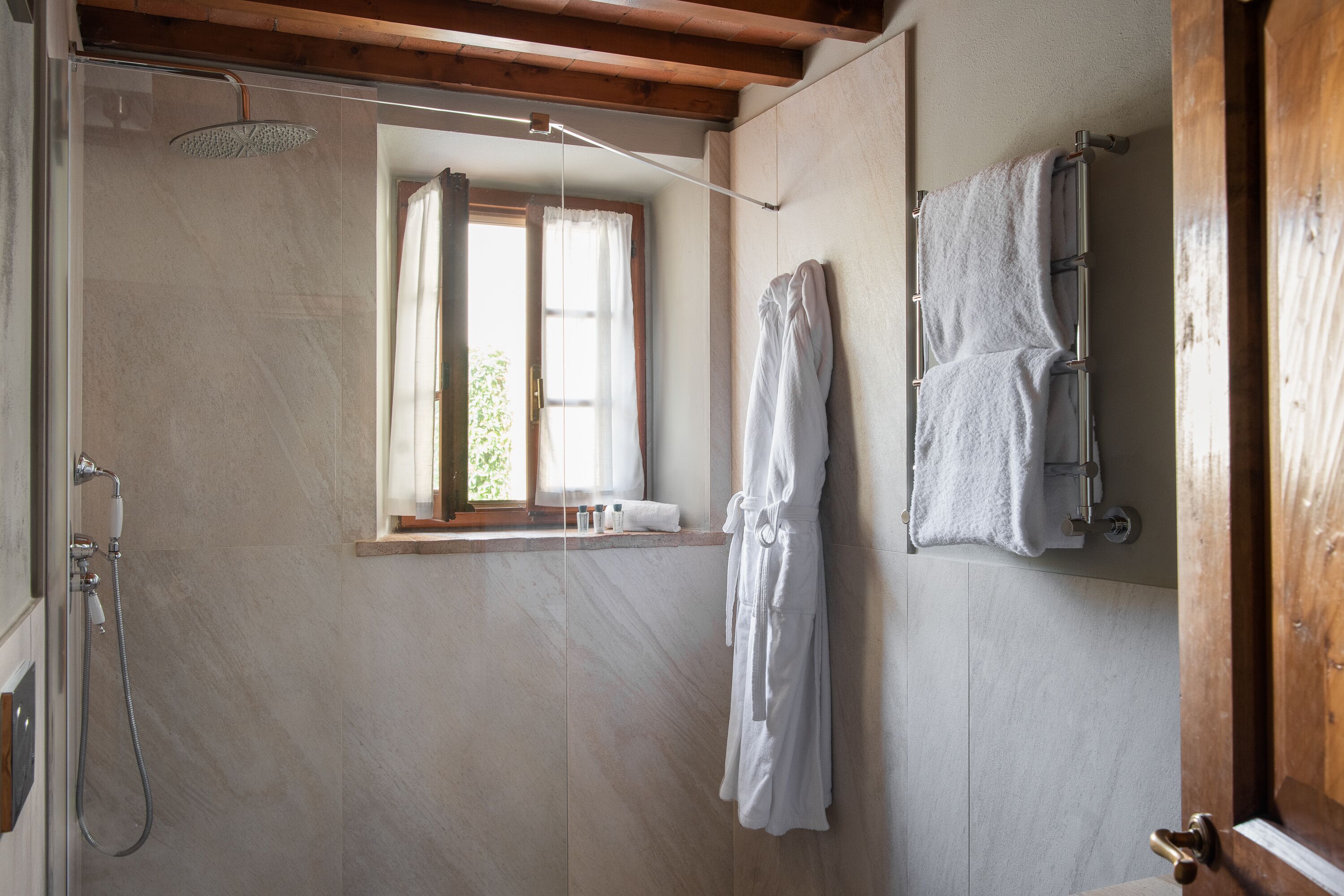 A bathroom with a shower, a window, and a towel rack.