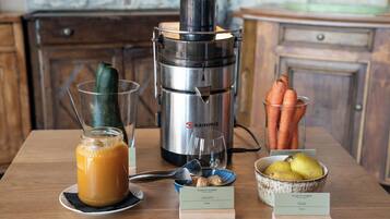 En køkkenbordplade med en juicer, et glas juice, en skål med ingefær, en skål med pærer og et glas juice.