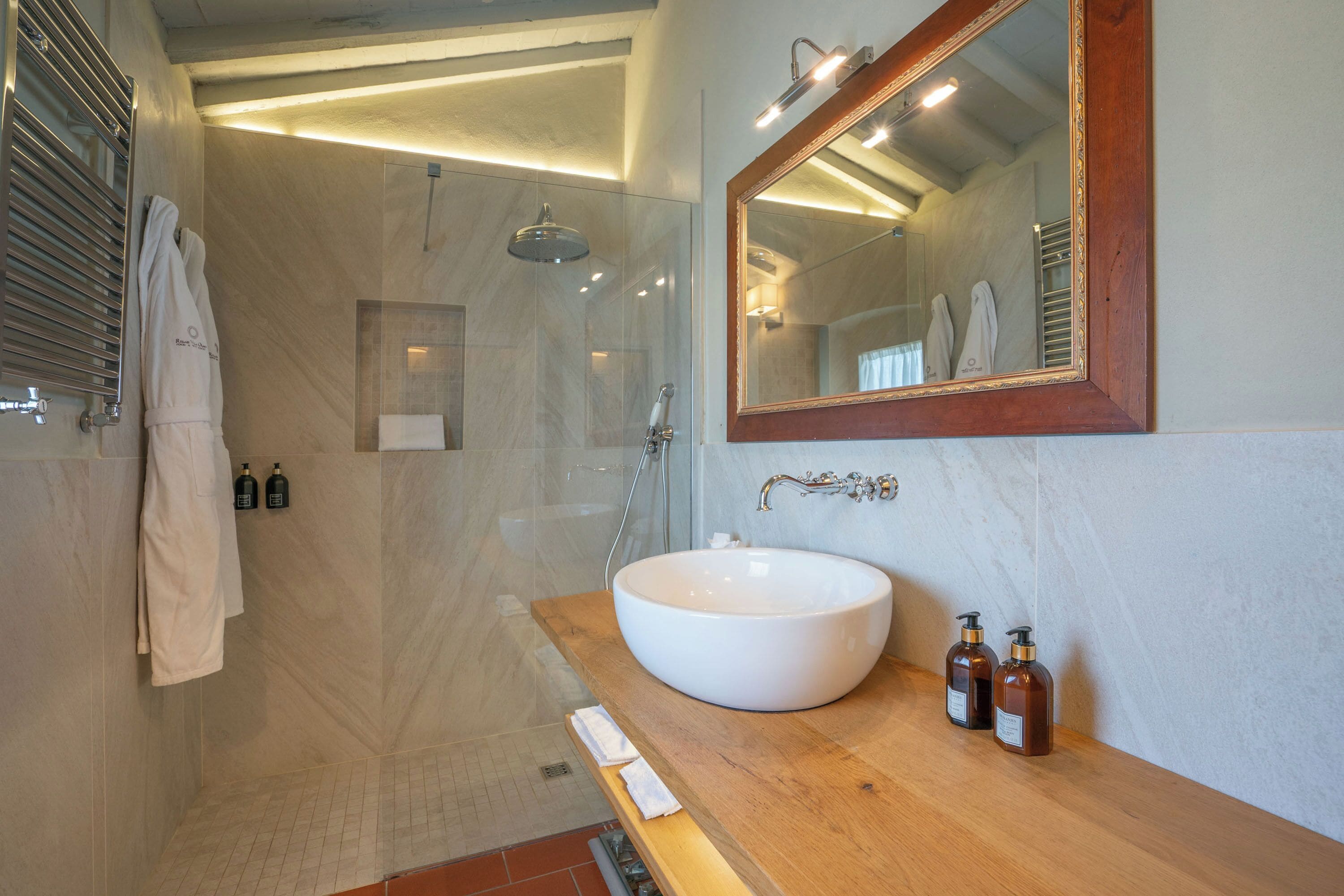Un baño moderno con un espejo grande, un lavabo redondo y una zona de ducha.
