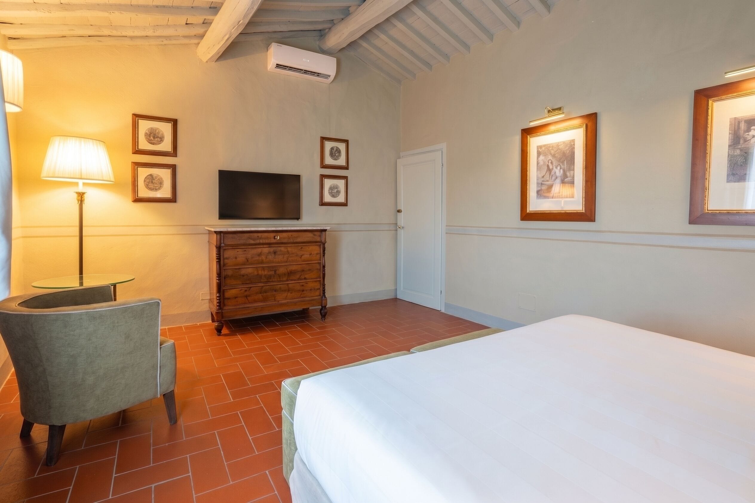 A hotel room with a bed, a desk with a chair, a television, and a dresser.