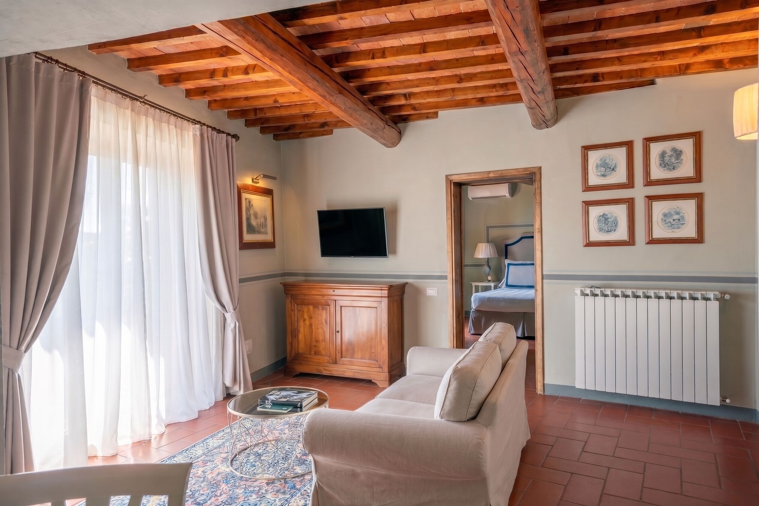 A living room with a wooden ceiling, a sofa, a television, and a radiator.
