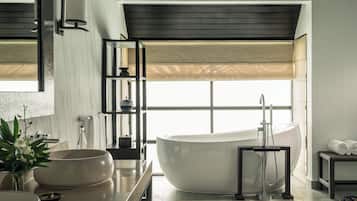 Un baño moderno con una bañera independiente, un espejo grande y una ventana con vistas.