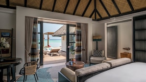 Ein Hotelzimmer mit einem großen Bett, einer Sitzecke mit Blick auf den Strand und einem Essbereich.