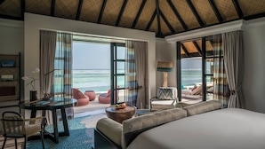 Ein Hotelzimmer mit einem großen Bett, einem Esstisch und Blick aufs Meer.