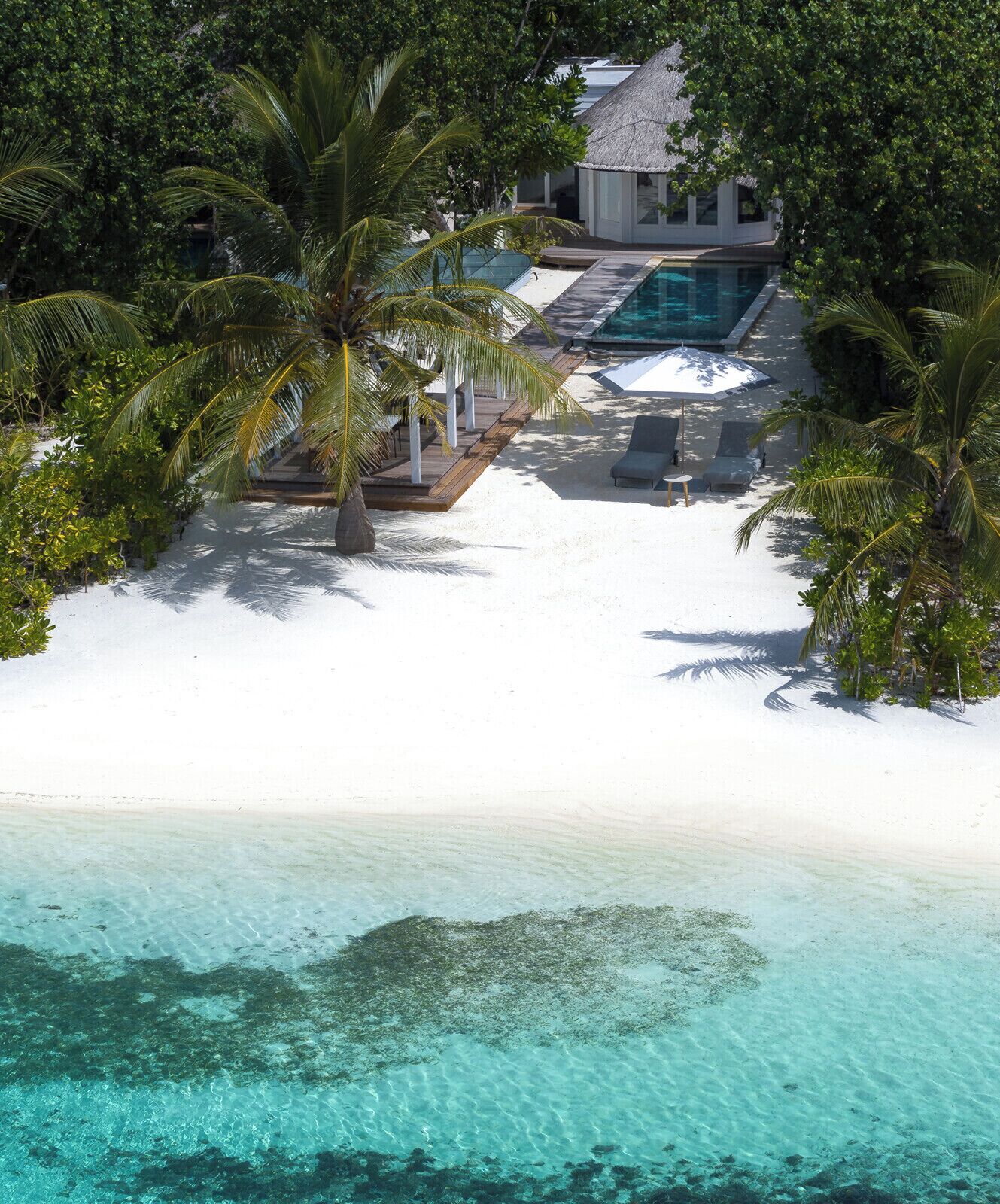 A resort with a swimming pool, lounge chairs, and a beach area.