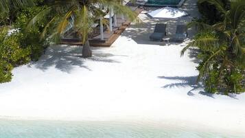 A resort with a swimming pool, lounge chairs, and a beach area.