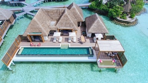 Bungalows auf Stelzen mit Swimmingpool, Holzterrasse und Reetdach.