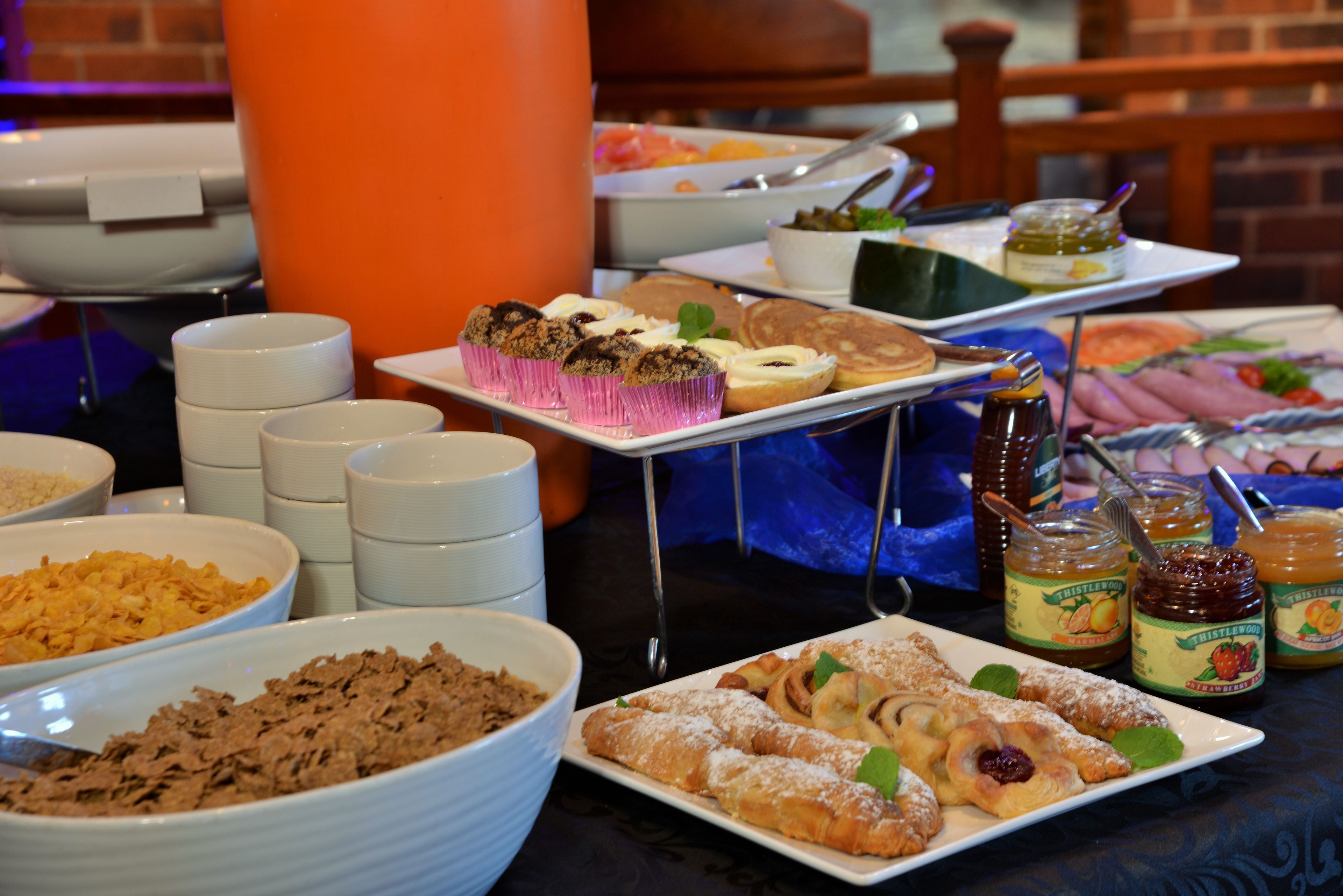 A buffet with various food items including pastries, cereals, and condiments.